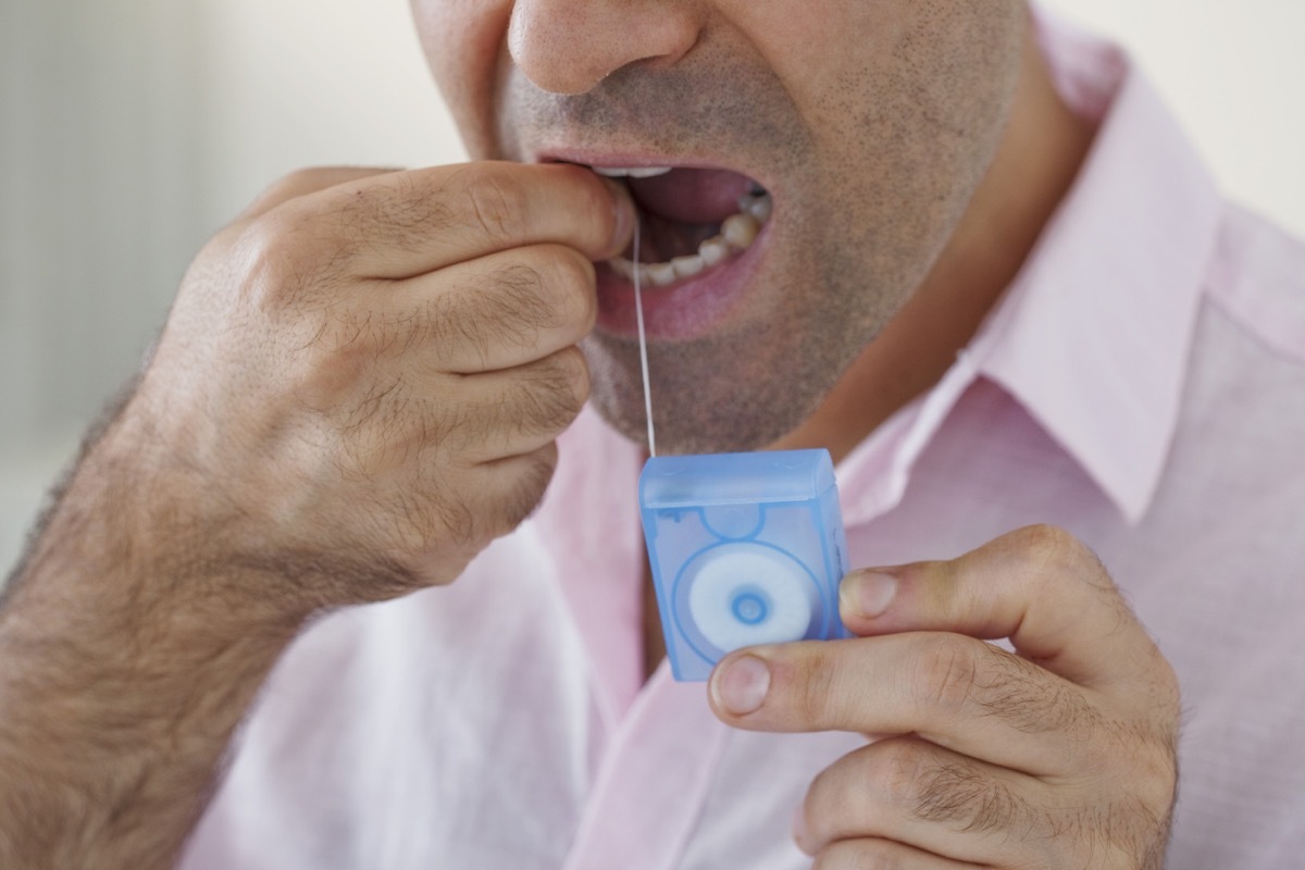 man flossing and wearing a pink shirt