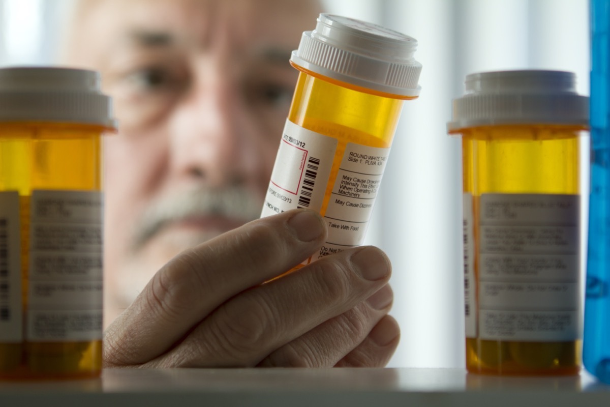 older white man holding prescription bottle