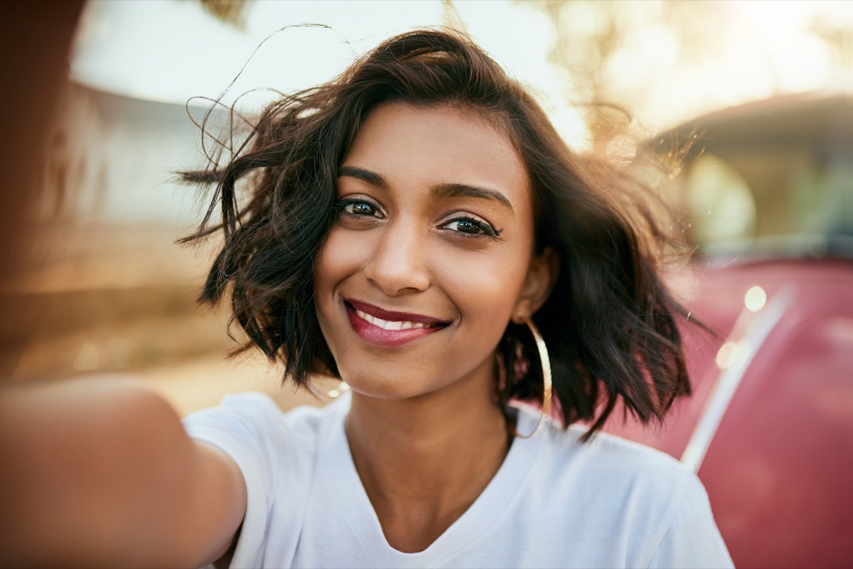 woman taking a selfie and smiling with her phone