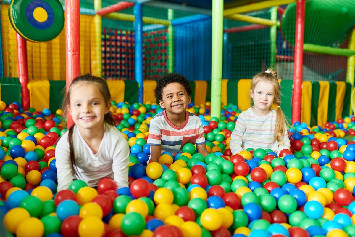 three kids playing in ball pit