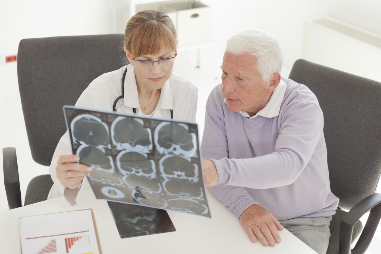 A senior man visiting with his doctor and looking at a CT scan of his brain