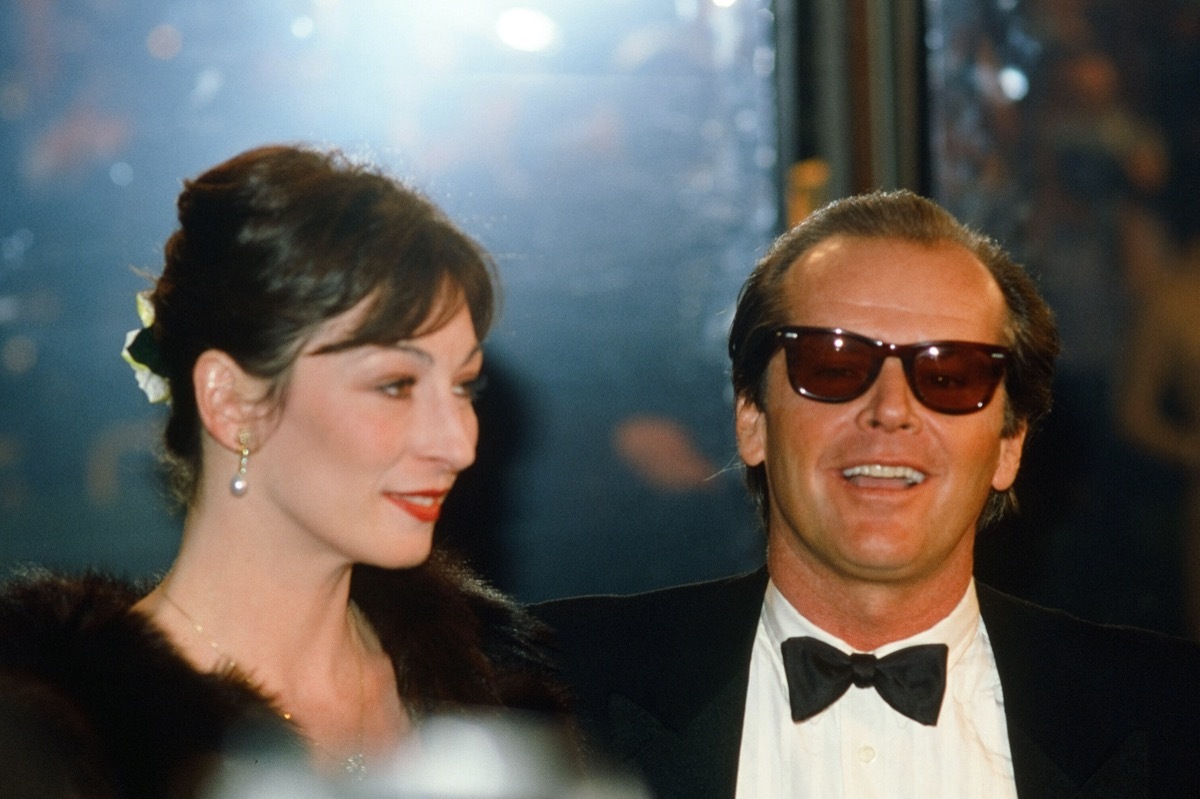 Anjelica Huston wears a black coat and Jack Nicholson wears a black suit at the American Film Institute Gala Tribute to John Huston in 1983