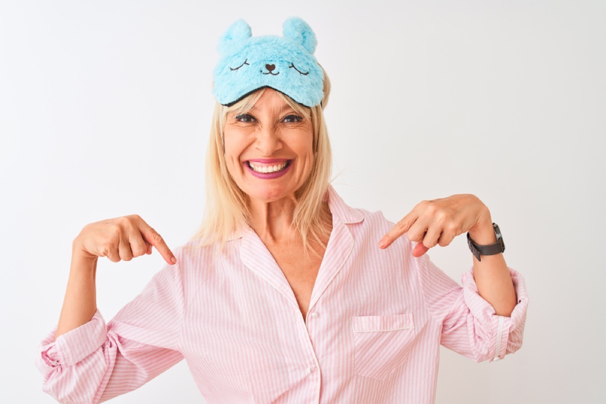 middle aged woman smiles in pink robe and blue bunny eye mask