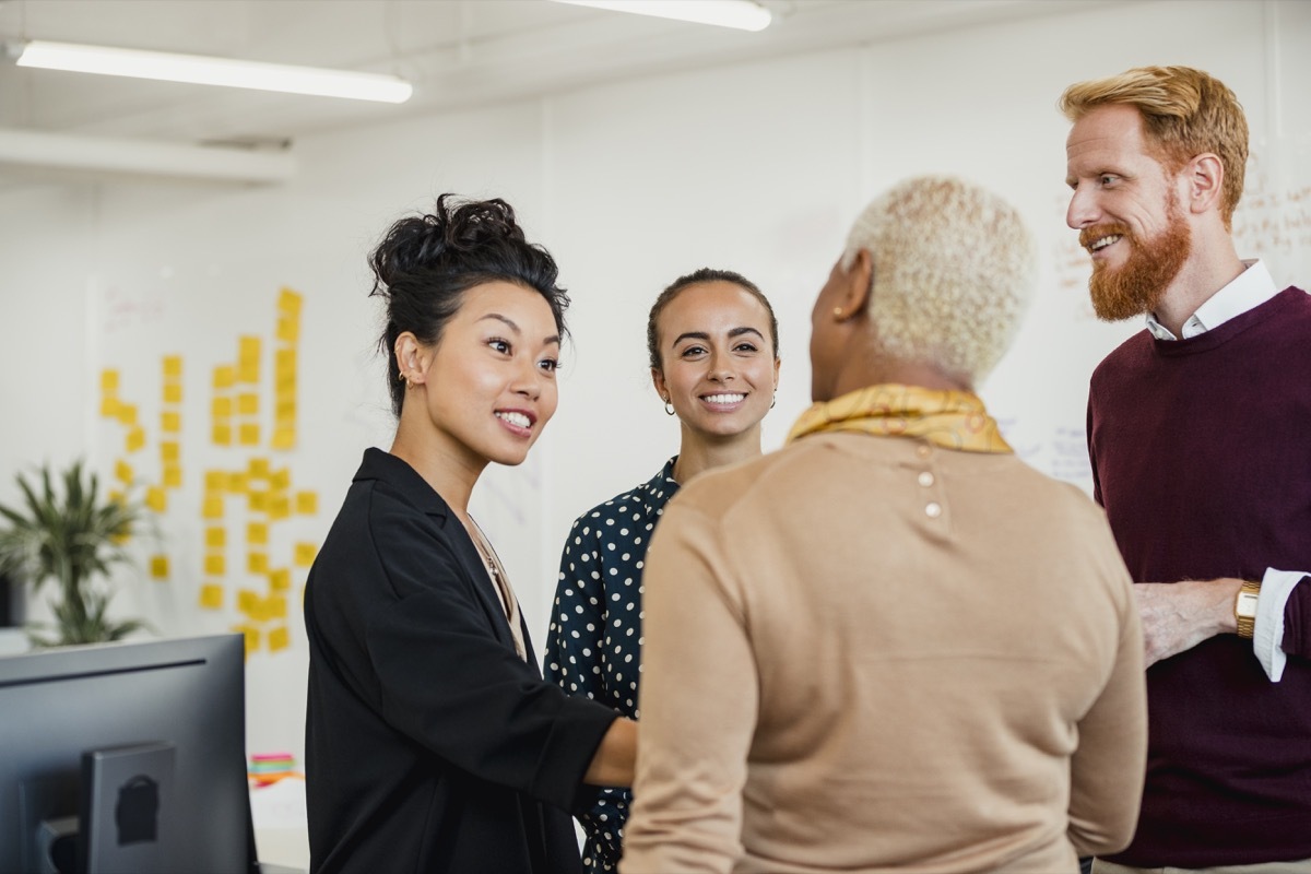 Colleagues standing in a small group discussing something while working at an office.