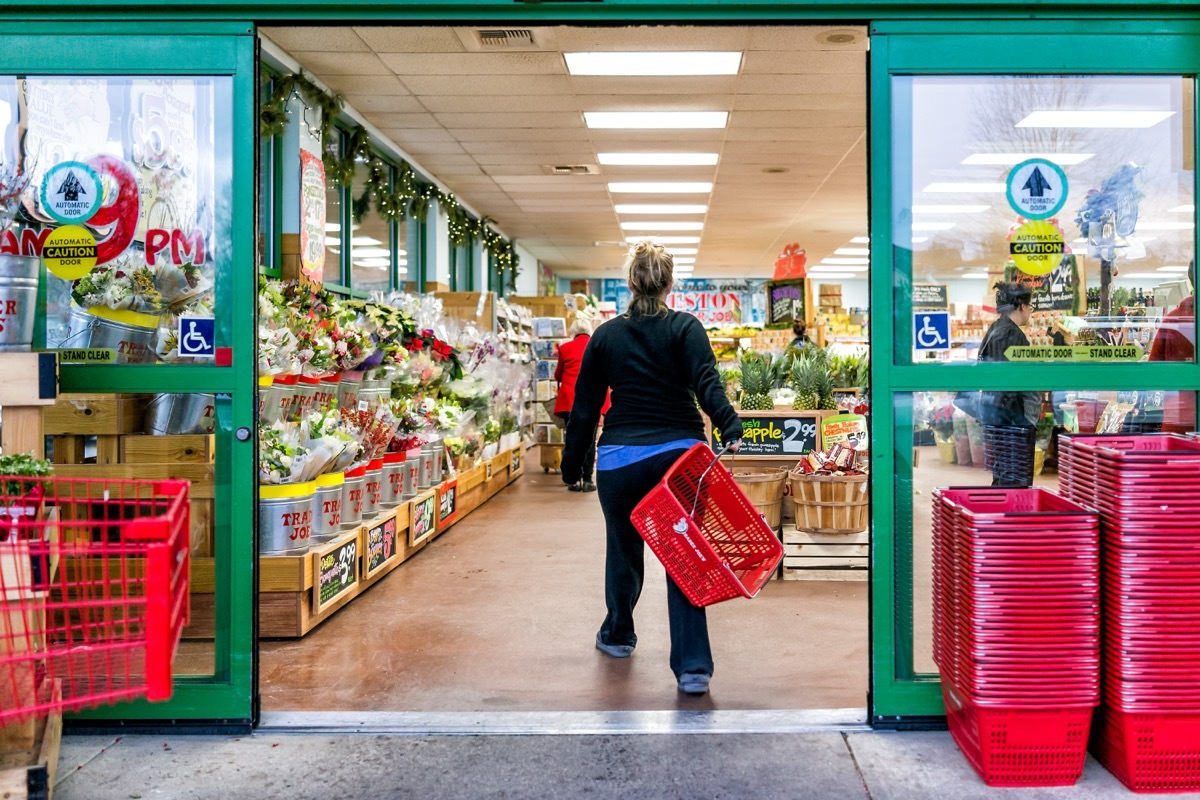 Trader Joe's customer trolley shopping basket carrying carts by store entrance doors outside women, winter flower pots, gardening plants, pineapple in Virginia