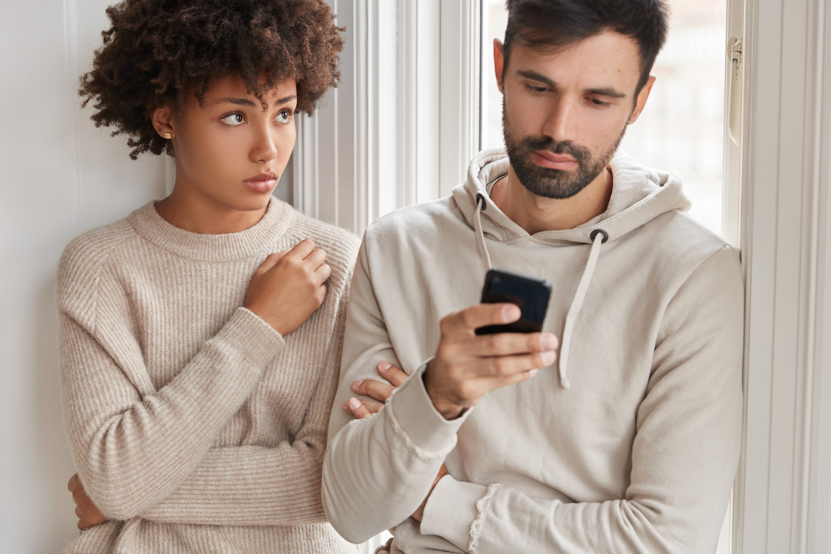 A man looking at his phone and ignoring the woman next to him.