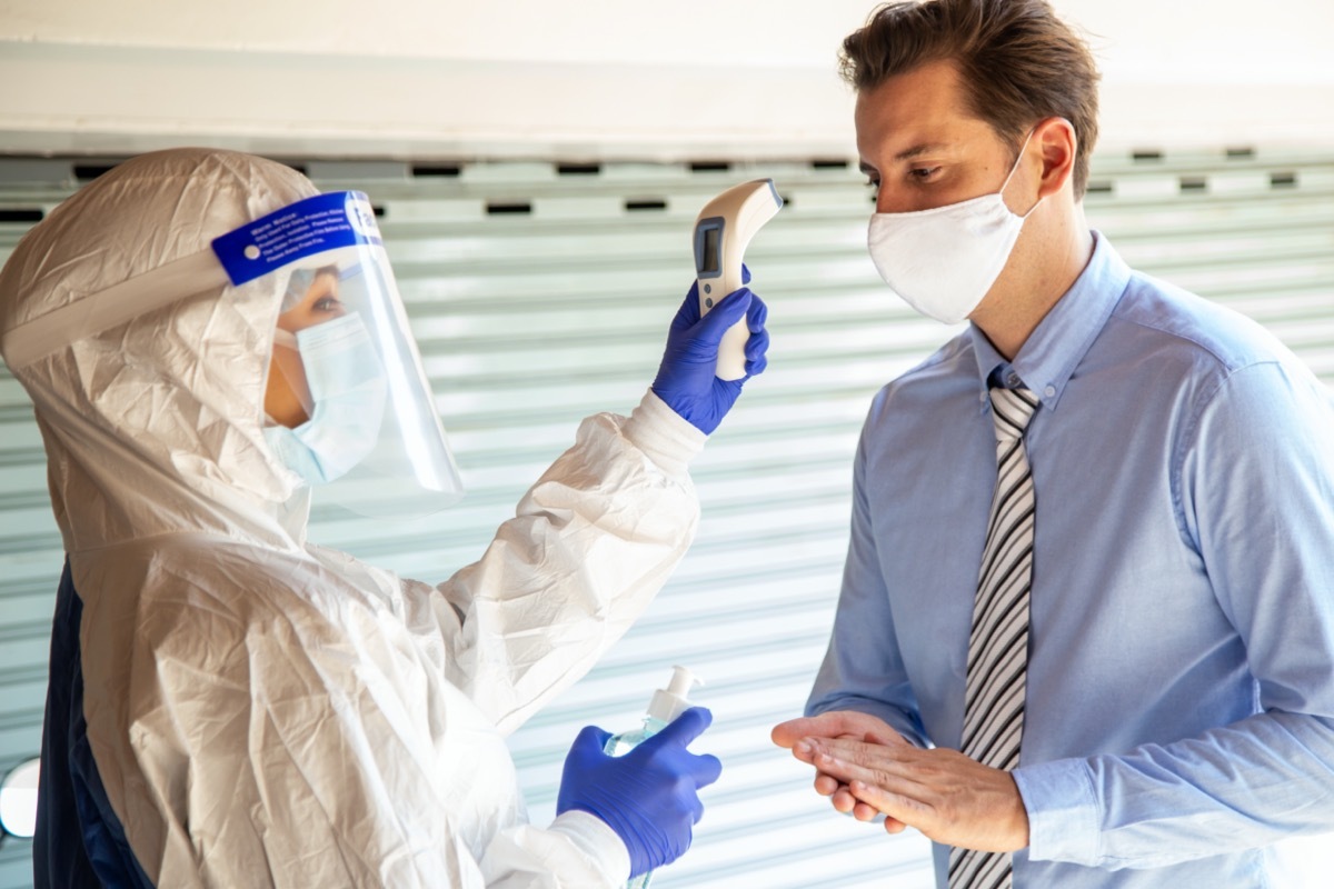 Officer use infrared forehead thermometer to check fever body temperature for virus symptoms