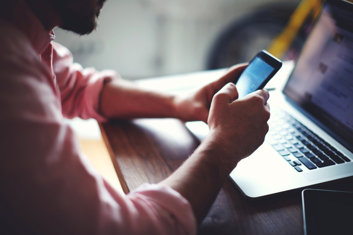 man using android in front of computer