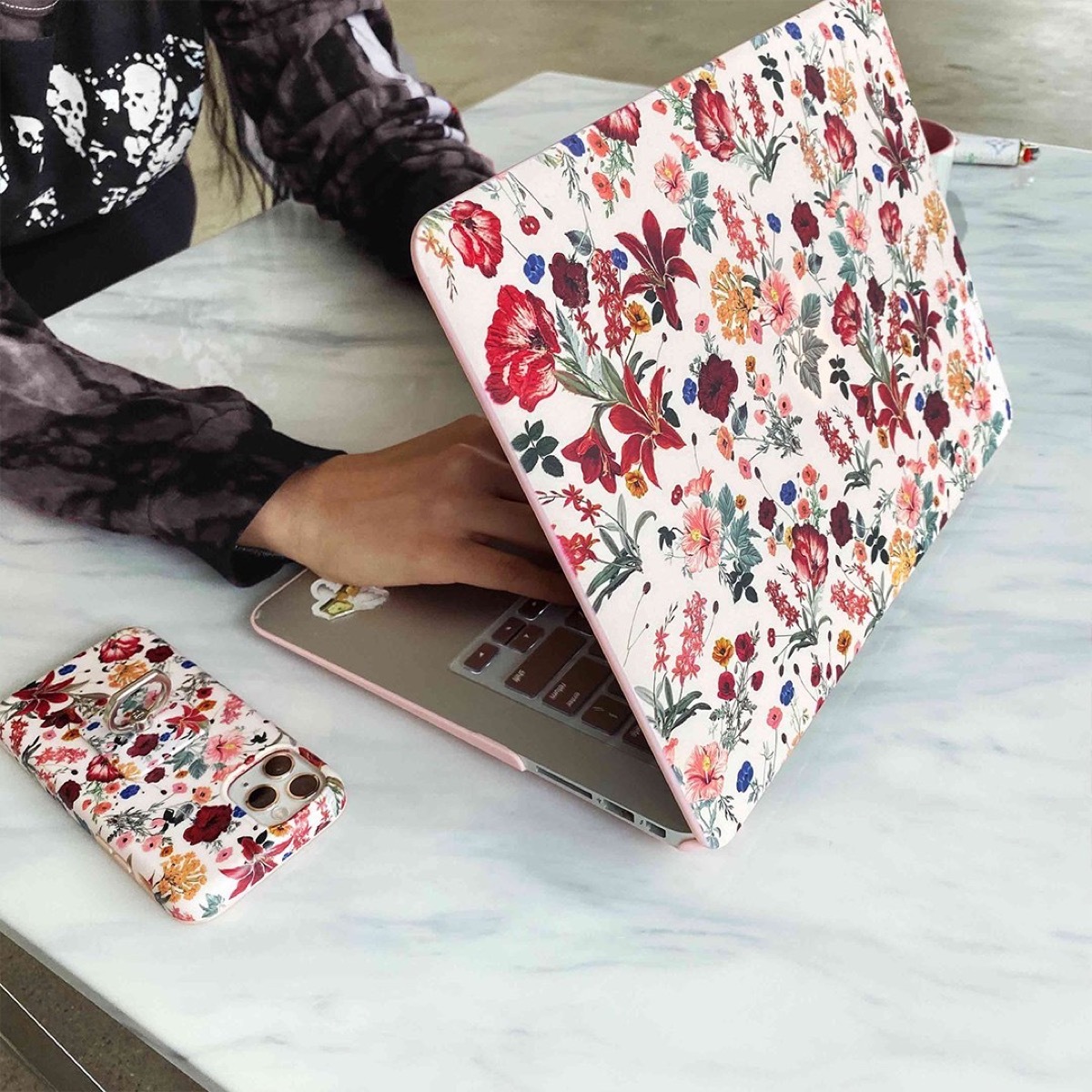 woman typing on floral-covered computer