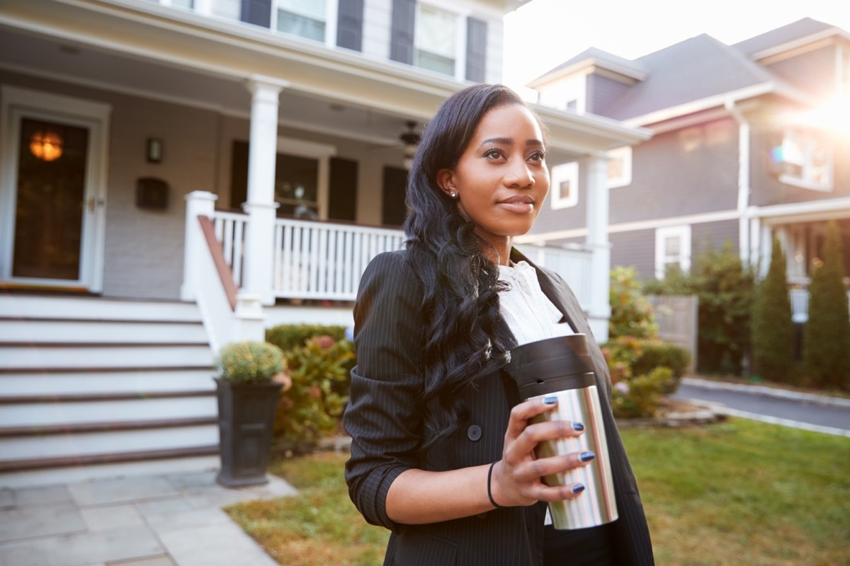 Black businesswoman drinking coffee in a to-go cup on her way to work