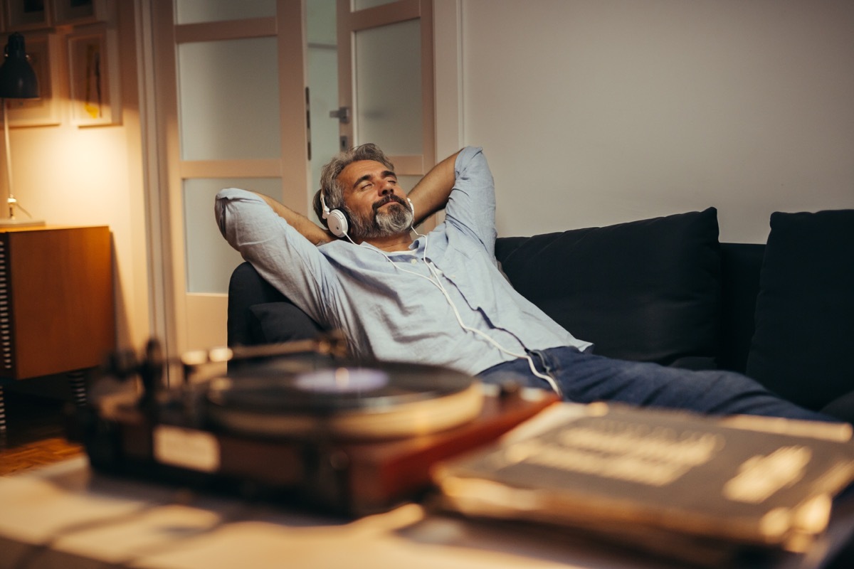 Man listening to headphones relaxing on his couch