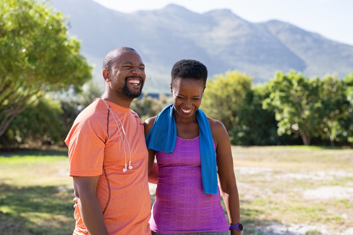 Cheerful black couple resting together after jogging in the park.