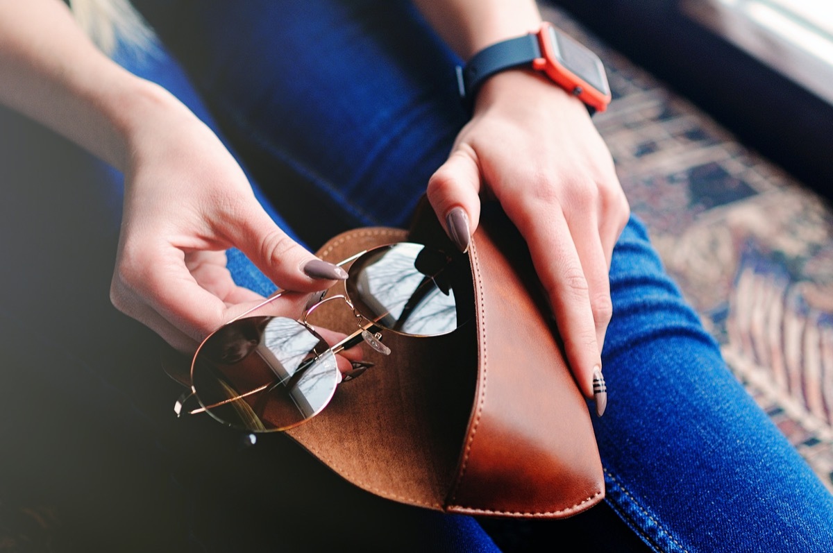 girl putting her sunglasses back in the case