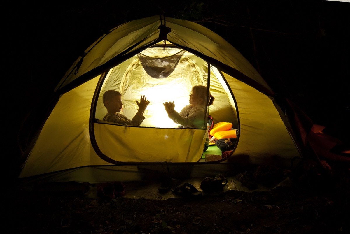 Kids camping in their backyard in a tent