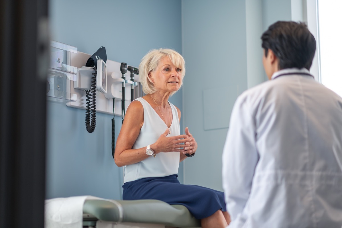 woman sitting on doctor bed trying to explain her problems to her doctor