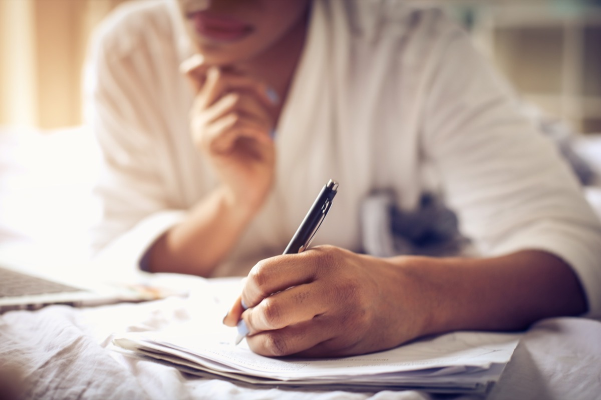 woman working at home and sign business paper. Focus is on hand. Close up. Space for copy.