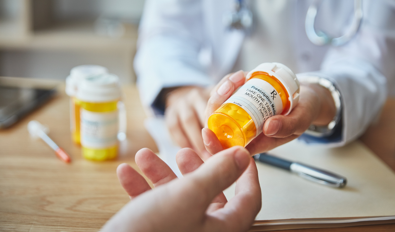 Pharmacist handing container of medication to customer. 