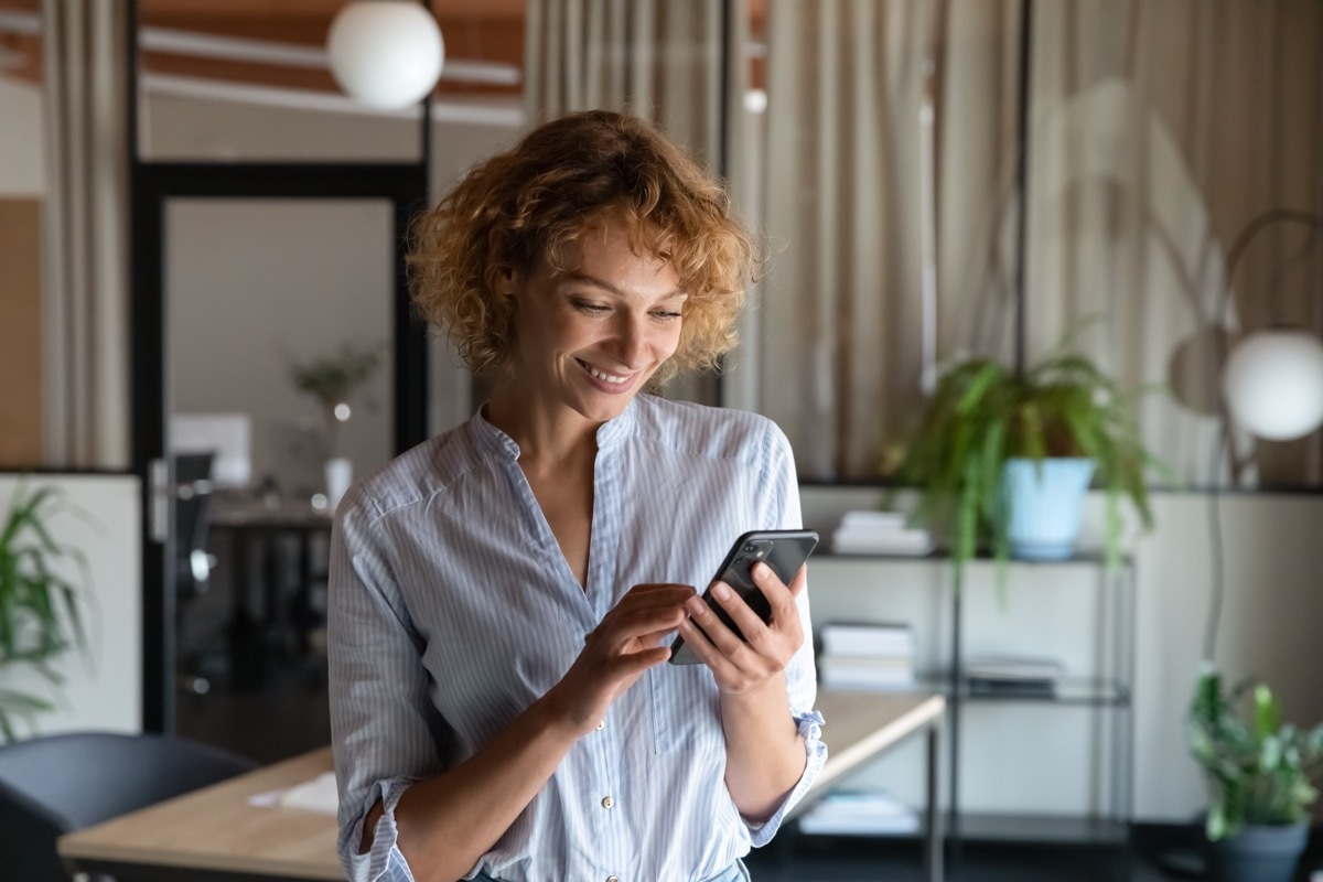 woman smiling while reading a text message