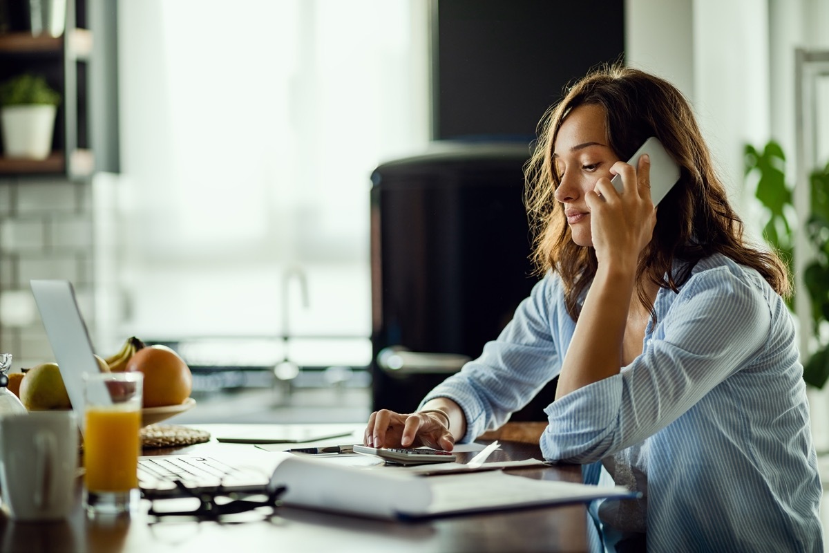 Young woman working on her home finances and communicating on mobile phone.