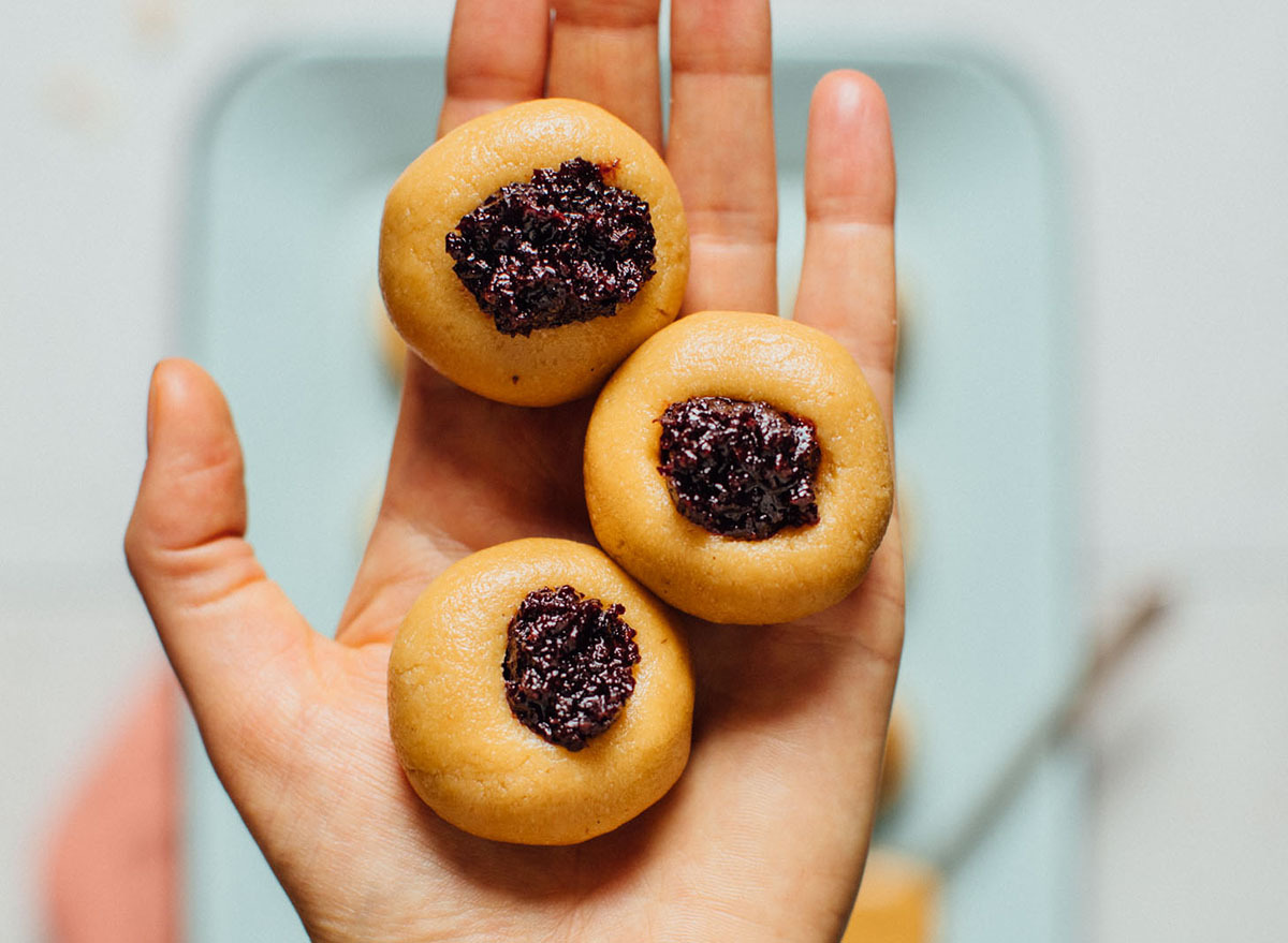 Holding three no bake peanut butter thumbprint cookies