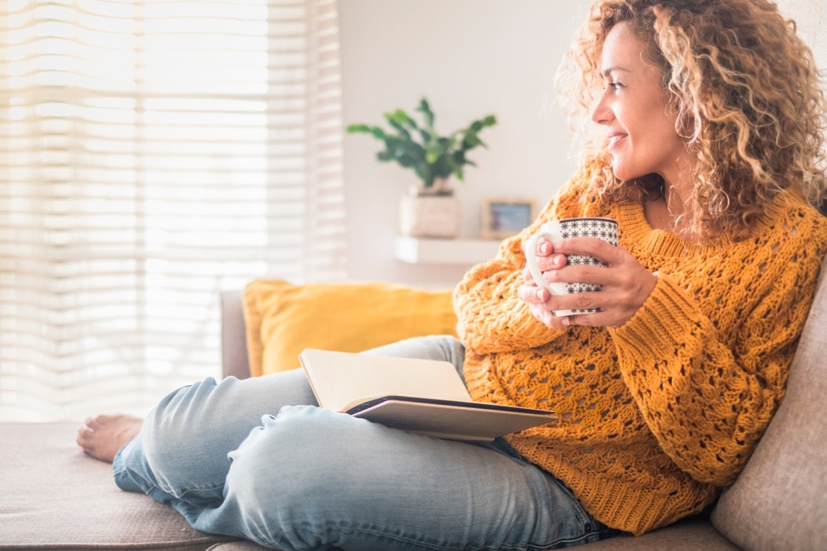 Woman drinking tea in a yellow sweater. 