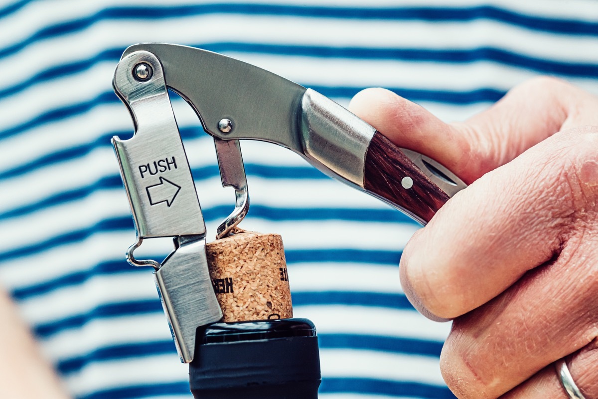 Close up of the removal of a cork from a wine bottle. The opener is the type which lifts the cork in two stages.