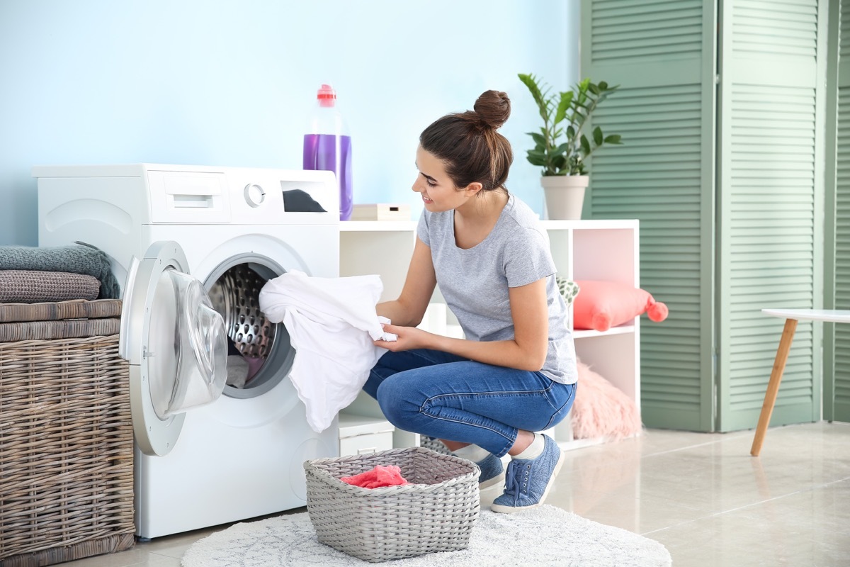 Woman putting linens in washing machine laundry room