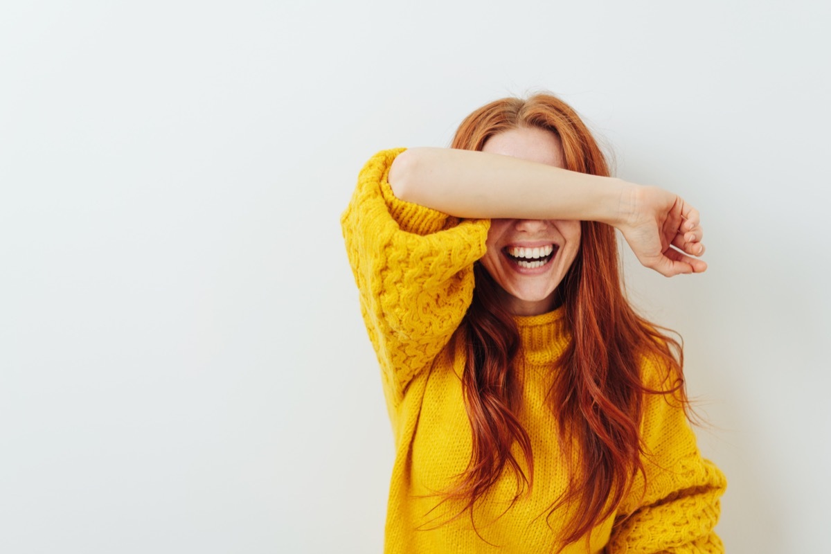 woman covering her eyes with her arm while laughing in response to unanswerable questions