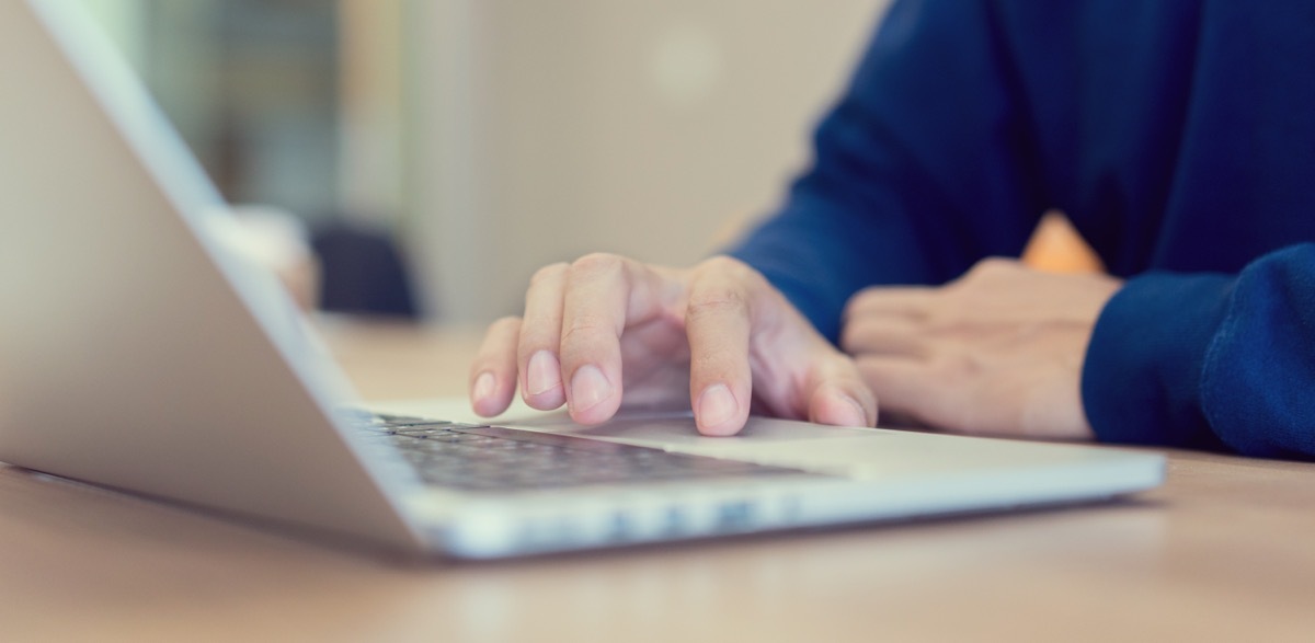 close up of man's hand on laptop track pad