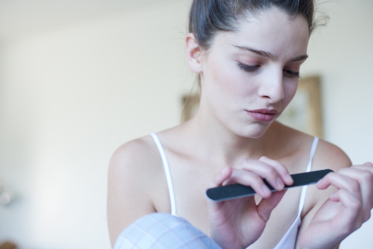 Woman using emery board on fingernails