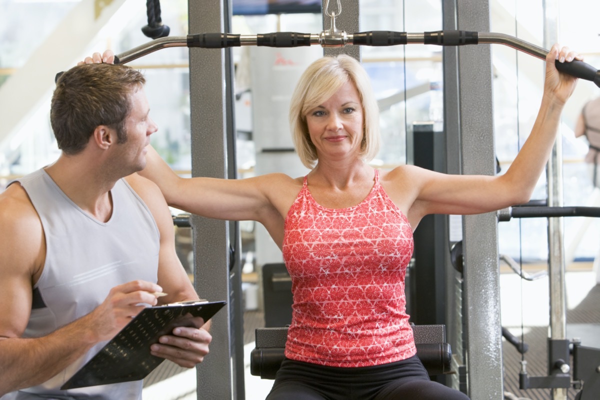 Personal Trainer Watching Woman Weight Train