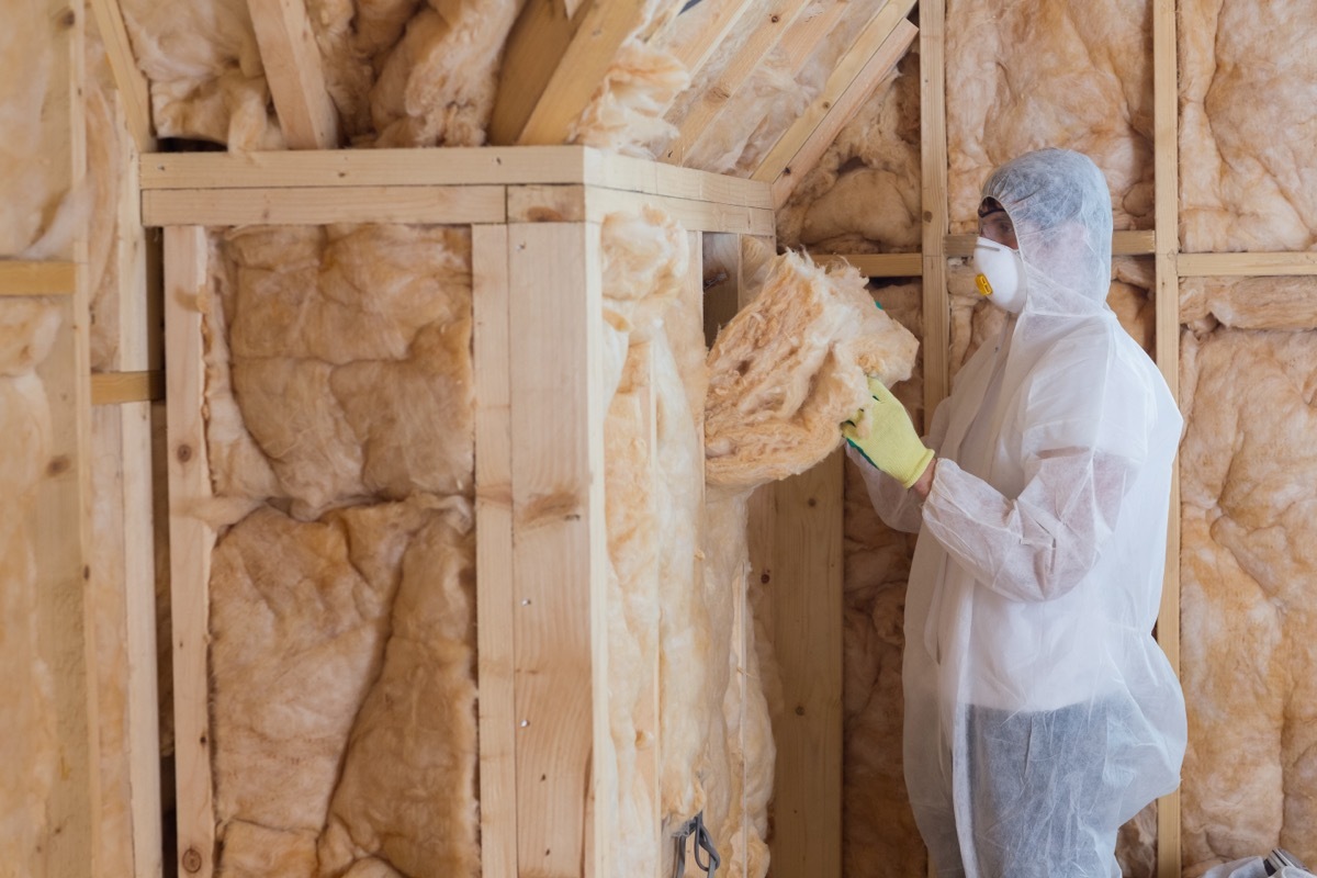 person in tyvek suit installing attic insulation