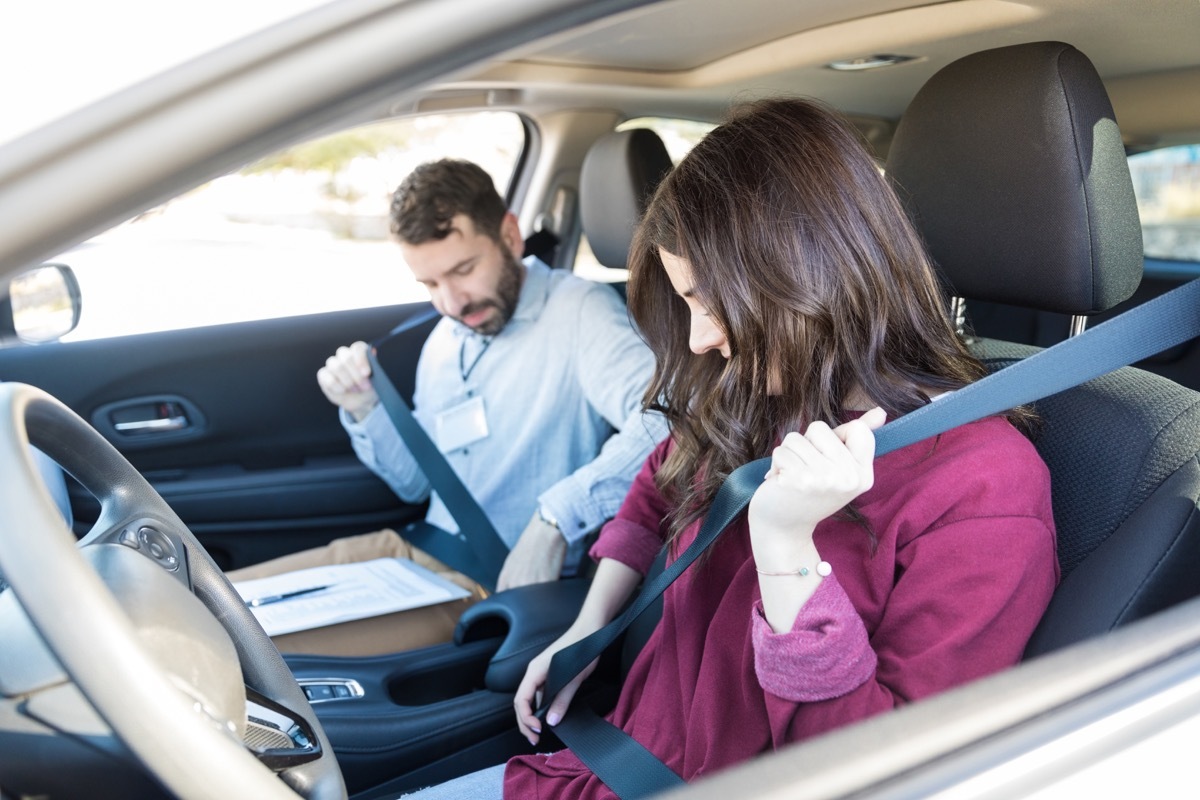 mid adult driver fastening seatbelts while sitting in car