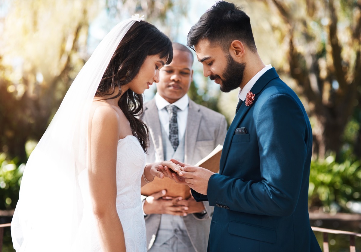 Cropped shot of an affectionate young groom slipping a ring on to his bride's finger while standing at the altar on their wedding day