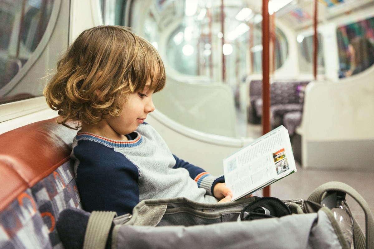 young boy reading on subway