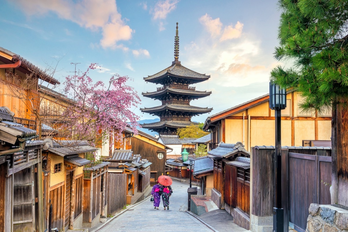 old town kyoto with two women dressed in kimonos walking down the road