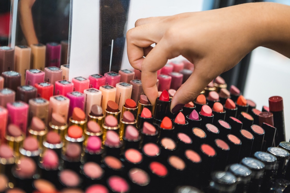 womans hand pulling out a lipstick from makeup stand