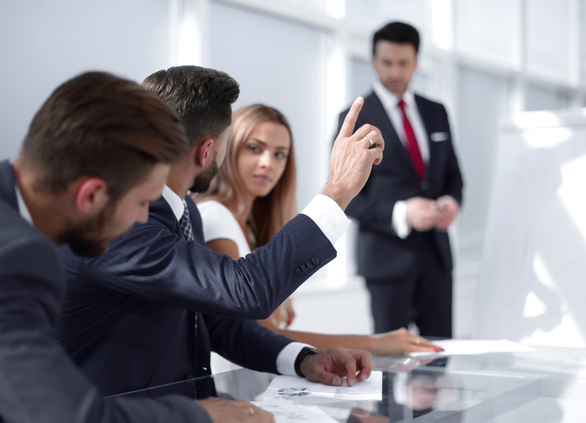 man apologizing in the workplace by raising his hand