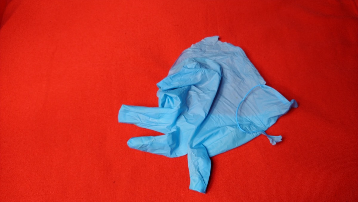 Broken medical glove on red background