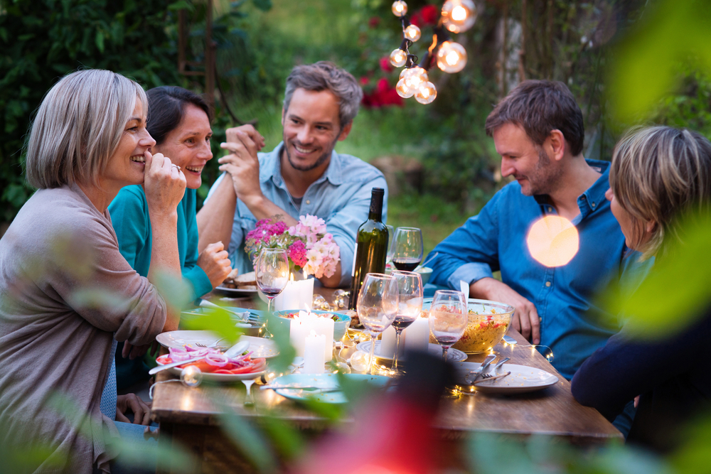 Group of middle aged friends at outdoor dinner party laughing