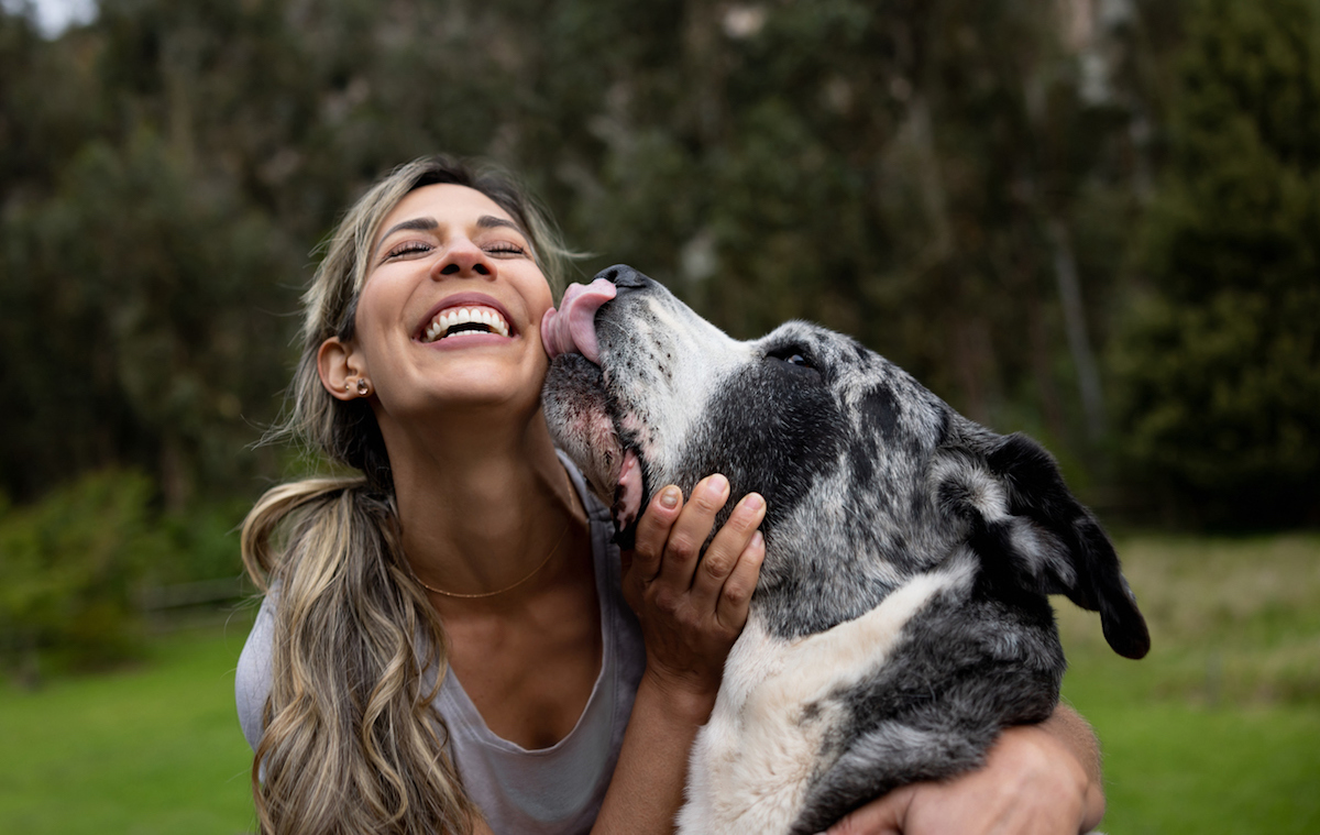 Happy woman playing with her dog outdoors