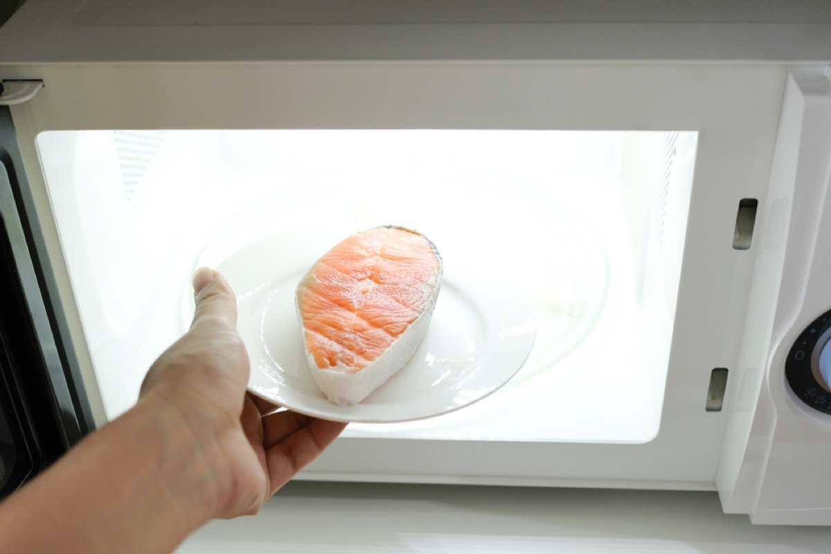 hand putting salmon filet into microwave, rude behavior