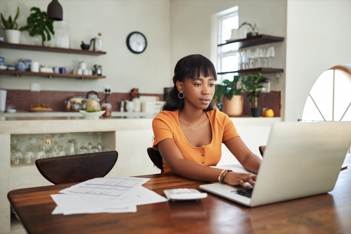 Shot of a young woman sitting with her laptop and paperwork at home