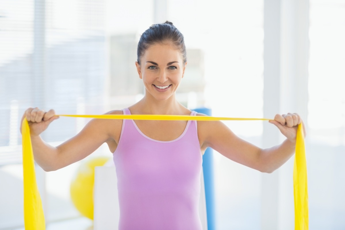 smiling woman holding resistance band at fitness studio