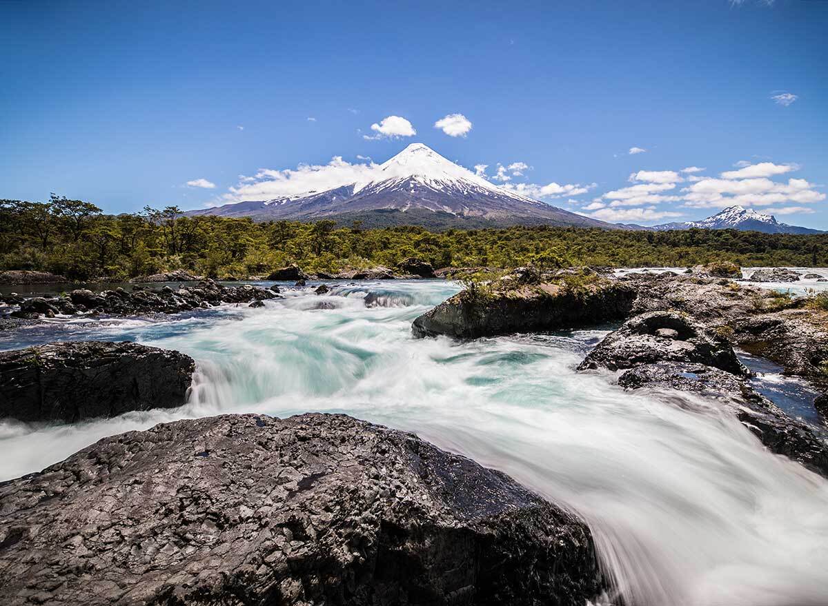 a rushing river with a mountain peak in the background