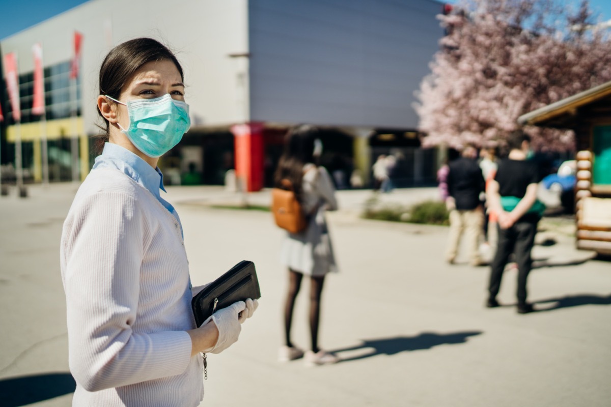 Shopper with mask standing in line to buy groceries due to coronavirus pandemic in grocery store