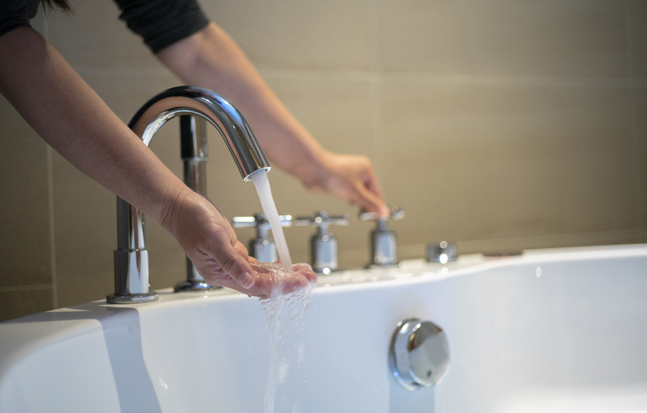 Person turning on water in bathtub.