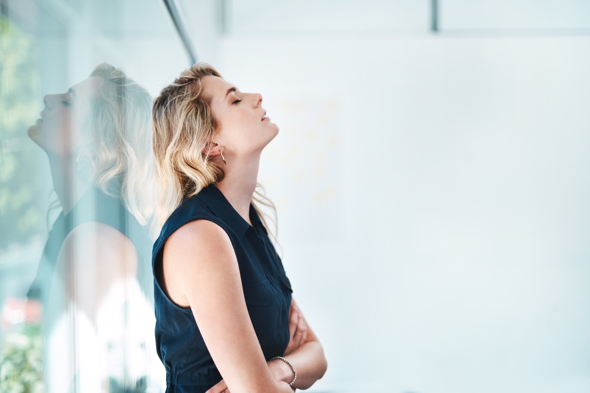 Exhausted woman resting against window