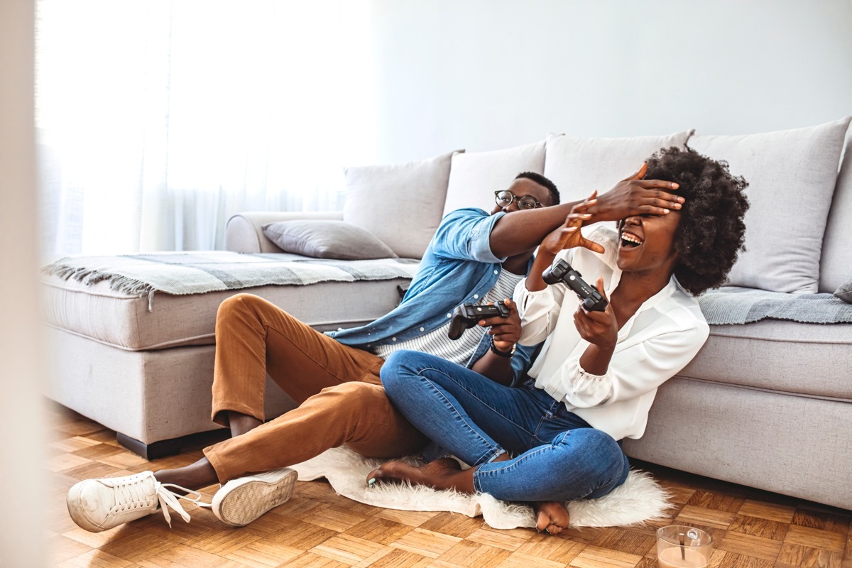 man and woman laughing while playing video games together