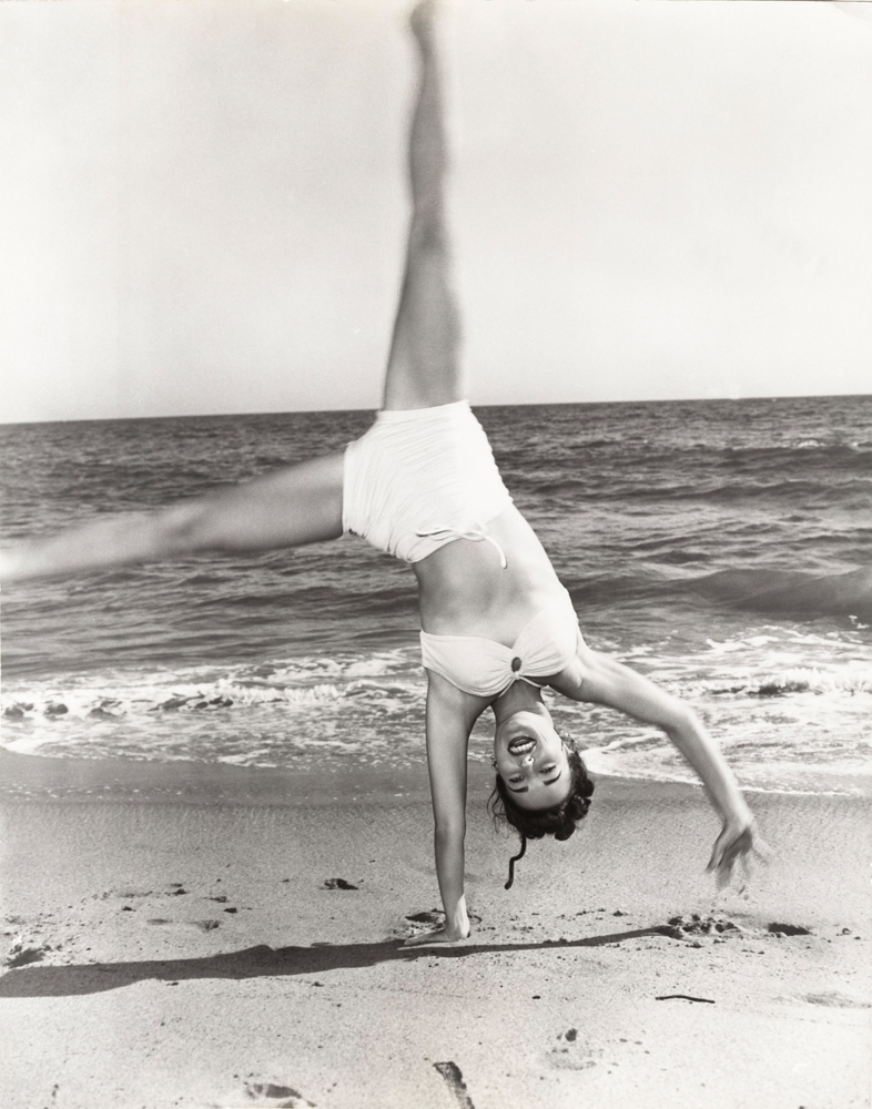 woman on beach doing cartwheel in bikini in 1940s